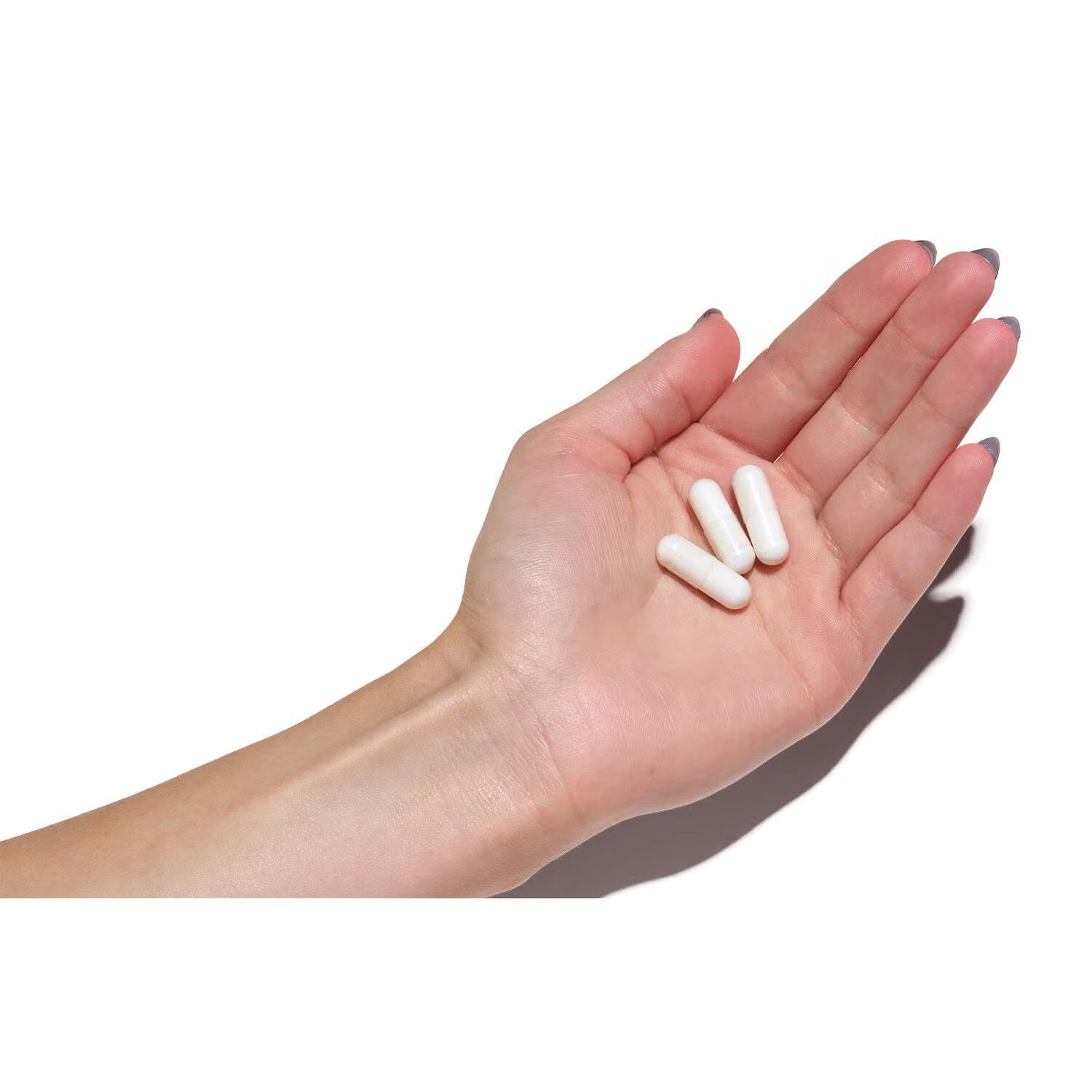 Hand holding 3 GNC Super Magnesium 300mg capsules – daily serving size for bone, heart & muscle support